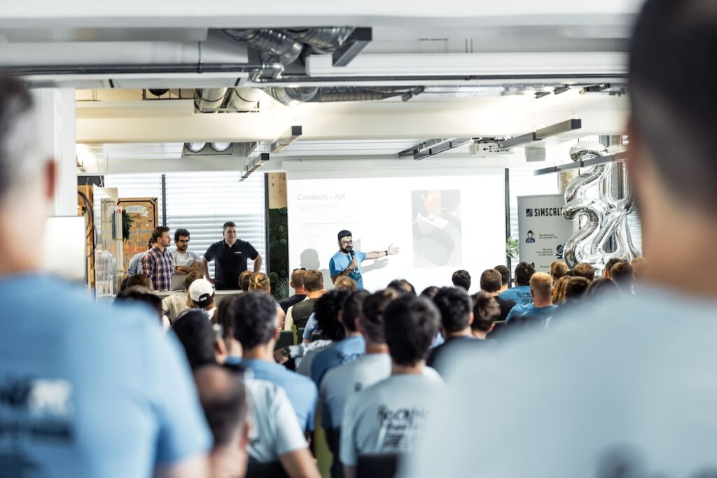 Man presenting slides in front of a room full of employees