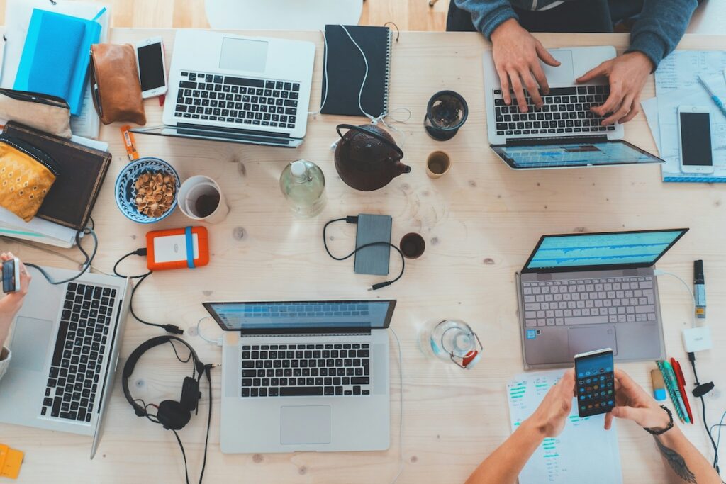 Laptops on a table with people working on them showing a collaborative environment