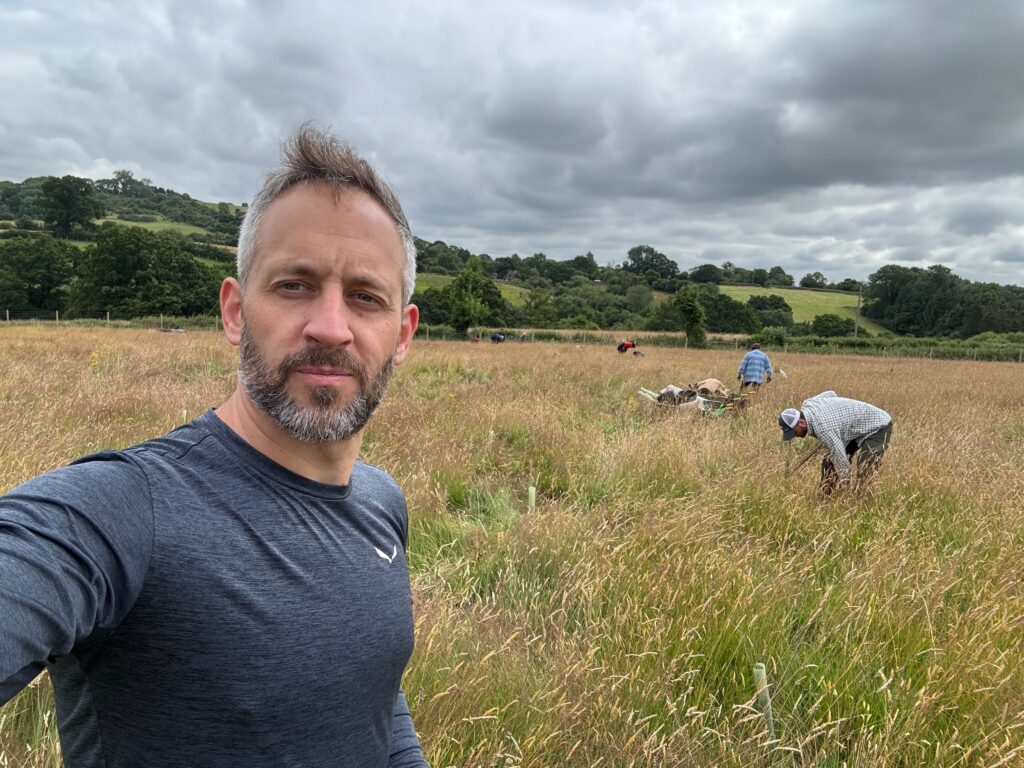 SimScale employee taking a selfie with farmers in the background re-wilding old farmlands in the UK